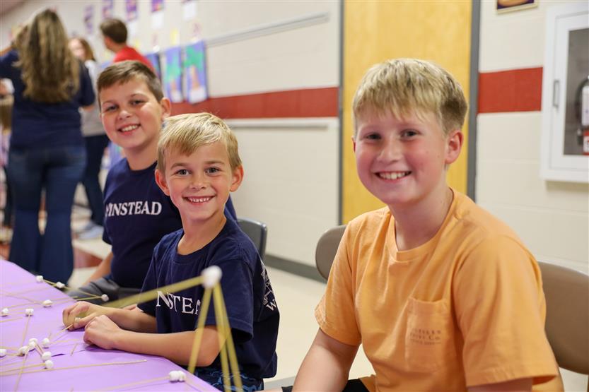 Students smile while sitting at a table